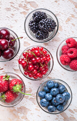 Forest fruit fresh berries in six glass jars reasy to eat arrangement on old painted kitchen wooden table front view studio shot
