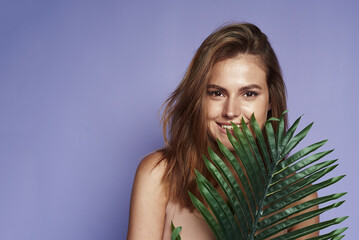 Fototapeta premium Cheerful pretty woman charm smile palm leaves. Leaf Of Palm Behind Model. Beautiful. Organic Cosmetic And SPA Treatment For Healthy Hydrated Facial Skin