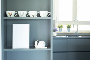 Elegant and cozy gray kitchen. Blank white frame mockup on the furniture shelf in the foreground....