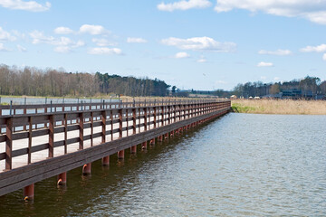 Fototapeta na wymiar wooden bridge over the lake, beautiful blue sky with clouds