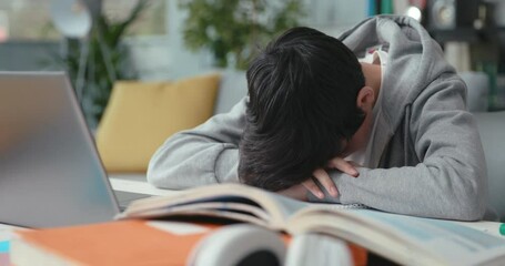 Exhausted student leaning his head on the desk - Powered by Adobe
