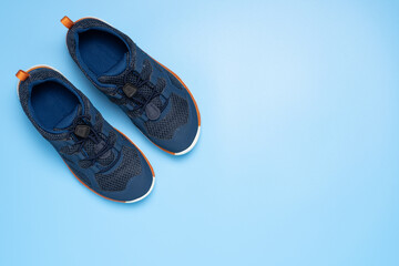 Pair of blue children sport sneakers or shoes on blue background, top view.