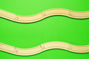 Rails or elements of toy wooden railroad on vivid green background.
