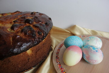 Easter pastries and colored eggs on a textile gold background. yellow silk. Easter composition. Traditional pastries for Orthodox holidays.