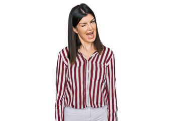 Beautiful brunette woman wearing striped shirt winking looking at the camera with sexy expression,...