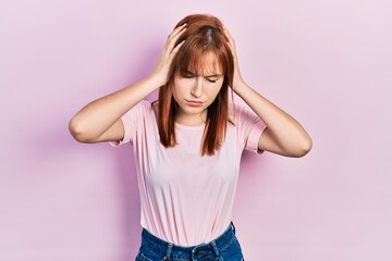 Redhead young woman wearing casual pink t shirt suffering from headache desperate and stressed because pain and migraine. hands on head.