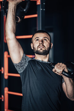 Photo of a sportsman exercising with a weight. Fitness man doing a weight training by lifting kettlebell. Young athlete doing kettlebell swings. Bodybuilder lifting kettlebell.