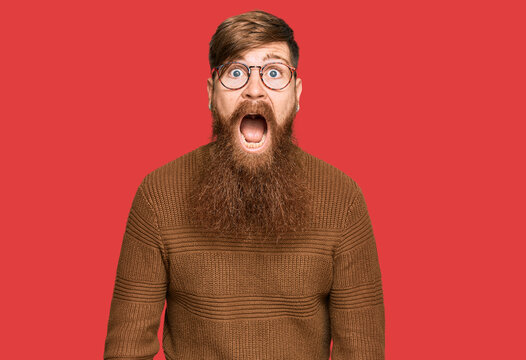 Young irish redhead man wearing casual clothes and glasses afraid and shocked with surprise and amazed expression, fear and excited face.