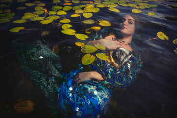 Mermaid with long red hair underwater with lily pads