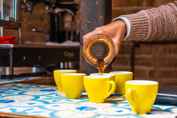 Professional barista preparing coffee using chemex pour over coffee maker and drip kettle. Alternative ways of brewing coffee. Coffee shop concept. Yellow cups