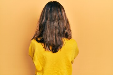 Young hispanic girl wearing casual clothes standing backwards looking away with crossed arms