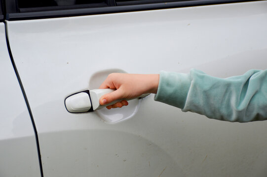 Female Hand Holding The Handle Of The Car And Trying To Open The Back Door