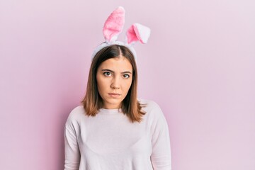 Young beautiful woman wearing cute easter bunny ears relaxed with serious expression on face. simple and natural looking at the camera.