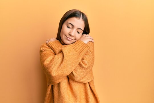 Young beautiful woman wearing turtleneck sweater hugging oneself happy and positive, smiling confident. self love and self care