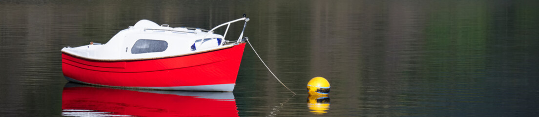 Single red boat alone on lake during summer
