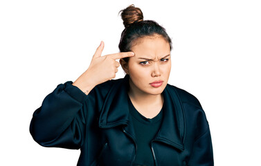 Young hispanic girl wearing sportswear pointing unhappy to pimple on forehead, ugly infection of...