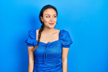 Young hispanic girl wearing casual clothes smiling looking to the side and staring away thinking.