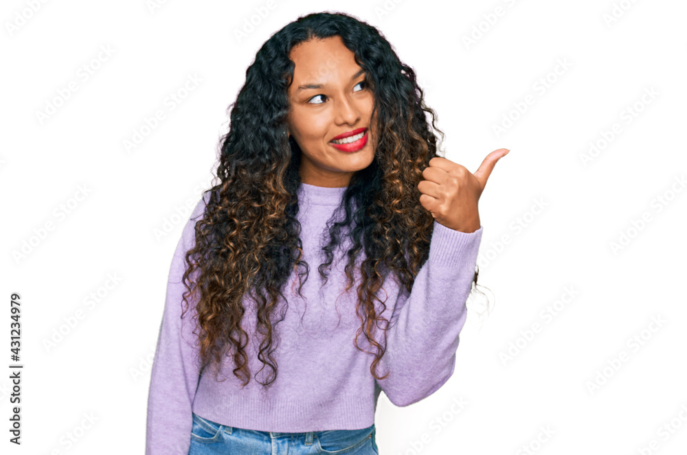 Wall mural young hispanic woman with curly hair wearing casual winter sweater smiling with happy face looking a