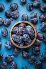 Fresh plums overhead ripe vibrant arrangement in old wooden jar on old blue kitchen table ready to eat studio shot
