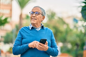 Senior grey-haired man smiling happy using smartphone at the city.