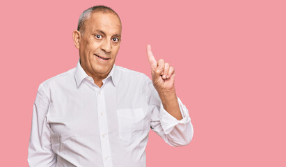 Handsome senior man wearing elegant white shirt showing and pointing up with finger number one while smiling confident and happy.