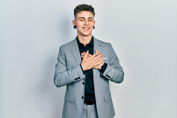 Young caucasian boy with ears dilation wearing business jacket smiling with hands on chest with closed eyes and grateful gesture on face. health concept.