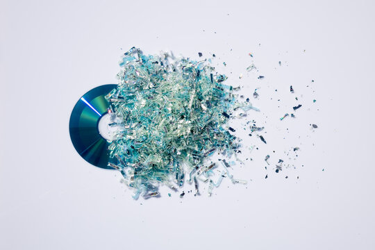 Datenvernichtung von CD oder DVD in Vielzahl funkelnder Teilchen auf weißer Platte