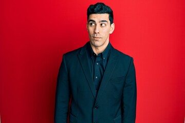 Handsome hispanic man wearing business clothes smiling looking to the side and staring away thinking.
