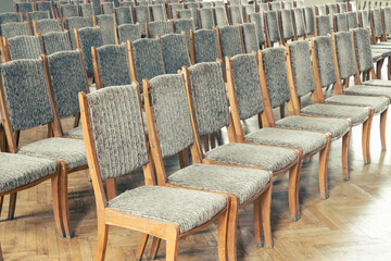 Rows of empty chairs. Wooden chairs with gray seats are in a straight line