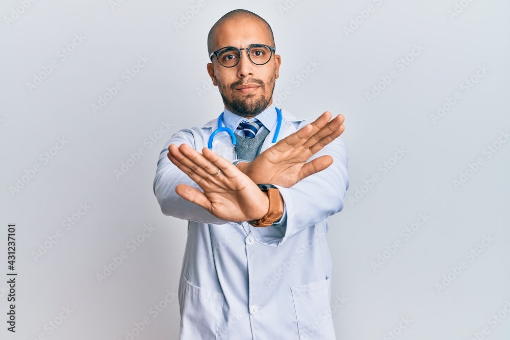 Wall mural Hispanic adult man wearing doctor uniform and stethoscope rejection expression crossing arms doing negative sign, angry face