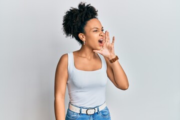 Young african american girl wearing casual style with sleeveless shirt shouting and screaming loud to side with hand on mouth. communication concept.