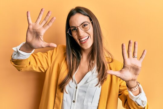 Young beautiful woman wearing business style and glasses showing and pointing up with fingers number ten while smiling confident and happy.