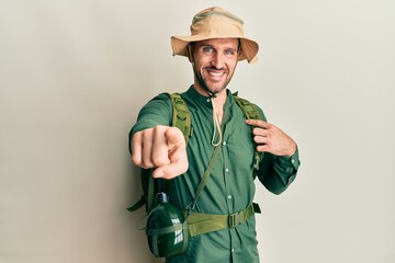 Fototapeta premium Handsome man with beard wearing explorer hat and backpack pointing to you and the camera with fingers, smiling positive and cheerful
