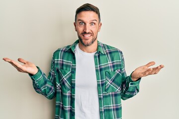 Handsome man with beard wearing casual clothes clueless and confused expression with arms and hands...
