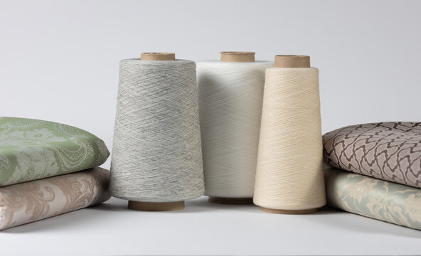 Vintage sewing thread on wooden spools with bed linen. on white isolated background. Copy space for text.