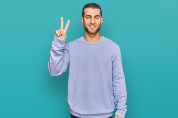 Fototapeta premium Young caucasian man wearing casual clothes showing and pointing up with fingers number two while smiling confident and happy.