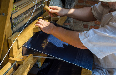 hands of man working on a manual loom to make denim blue jeans indigo vintage