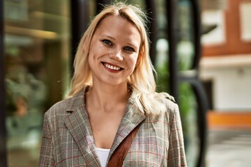 Young blonde businesswoman smiling happy standing at the city.