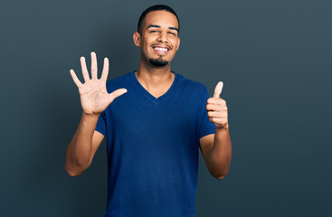 Young african american man wearing casual t shirt showing and pointing up with fingers number six while smiling confident and happy.