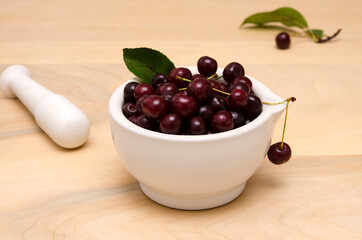 yummy berries cherries in a bowl and a pestle on the wooden table