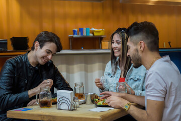Two men and a woman sitting talking and eating in a restaurant