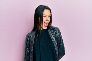 Fototapeta premium Young hispanic girl wearing party jacket winking looking at the camera with sexy expression, cheerful and happy face.