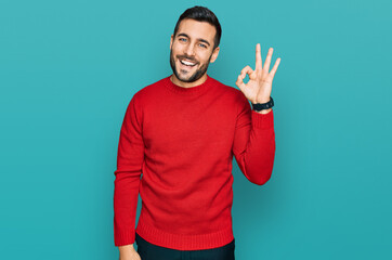 Young hispanic man wearing casual clothes smiling positive doing ok sign with hand and fingers....