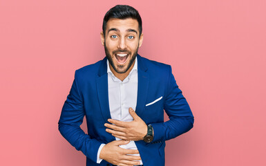 Young hispanic man wearing business jacket smiling and laughing hard out loud because funny crazy...