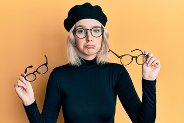 Young blonde girl wearing many glass over face depressed and worry for distress, crying angry and...