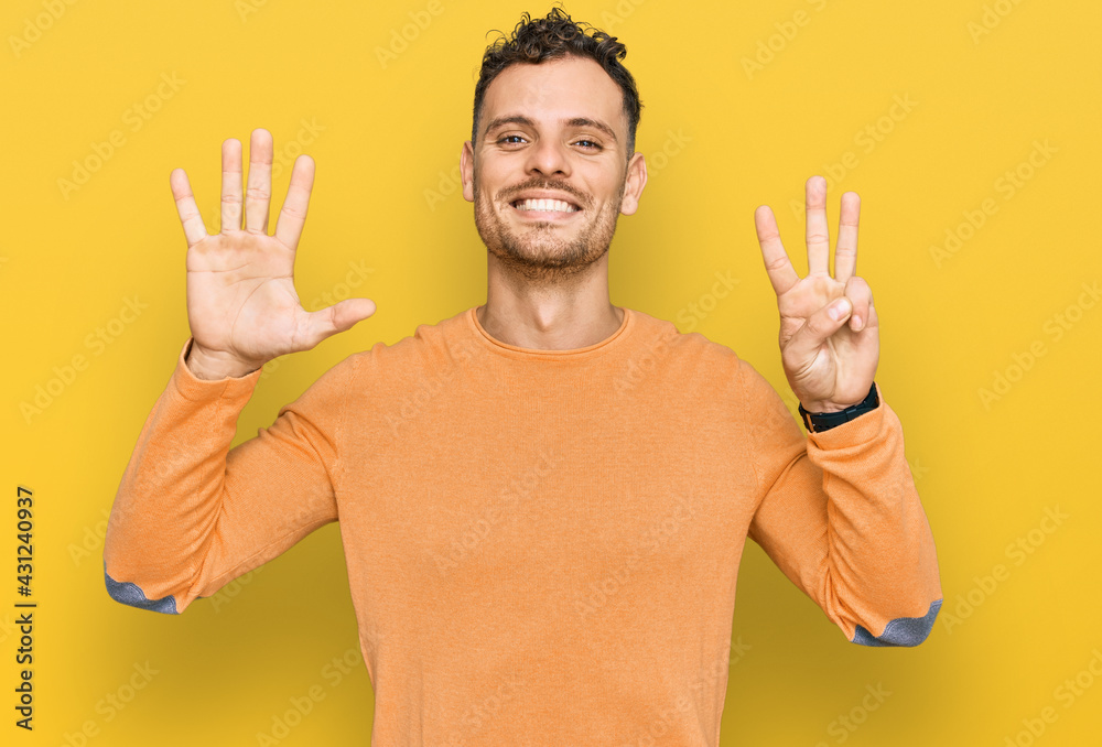 Wall mural young hispanic man wearing casual clothes showing and pointing up with fingers number eight while sm