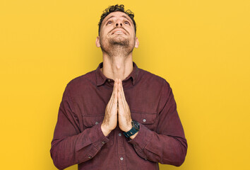 Young hispanic man wearing casual clothes begging and praying with hands together with hope...