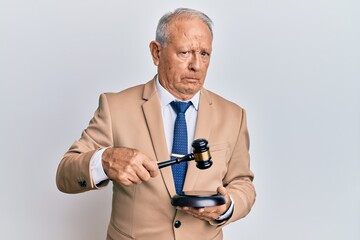 Senior caucasian judge man using gavel skeptic and nervous, frowning upset because of problem....