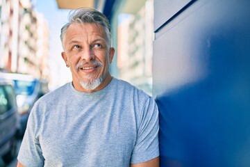 Middle age hispanic grey-haired man smiling happy standing at the city.