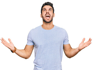 Fototapeta premium Young hispanic man wearing casual clothes crazy and mad shouting and yelling with aggressive expression and arms raised. frustration concept.
